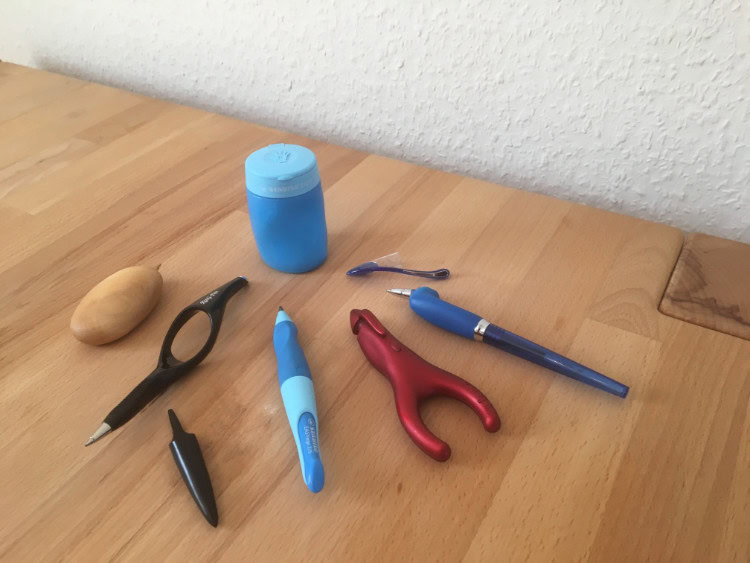 Verschiedene ergonomische Stifte und Schreibhilfen auf dem Tisch