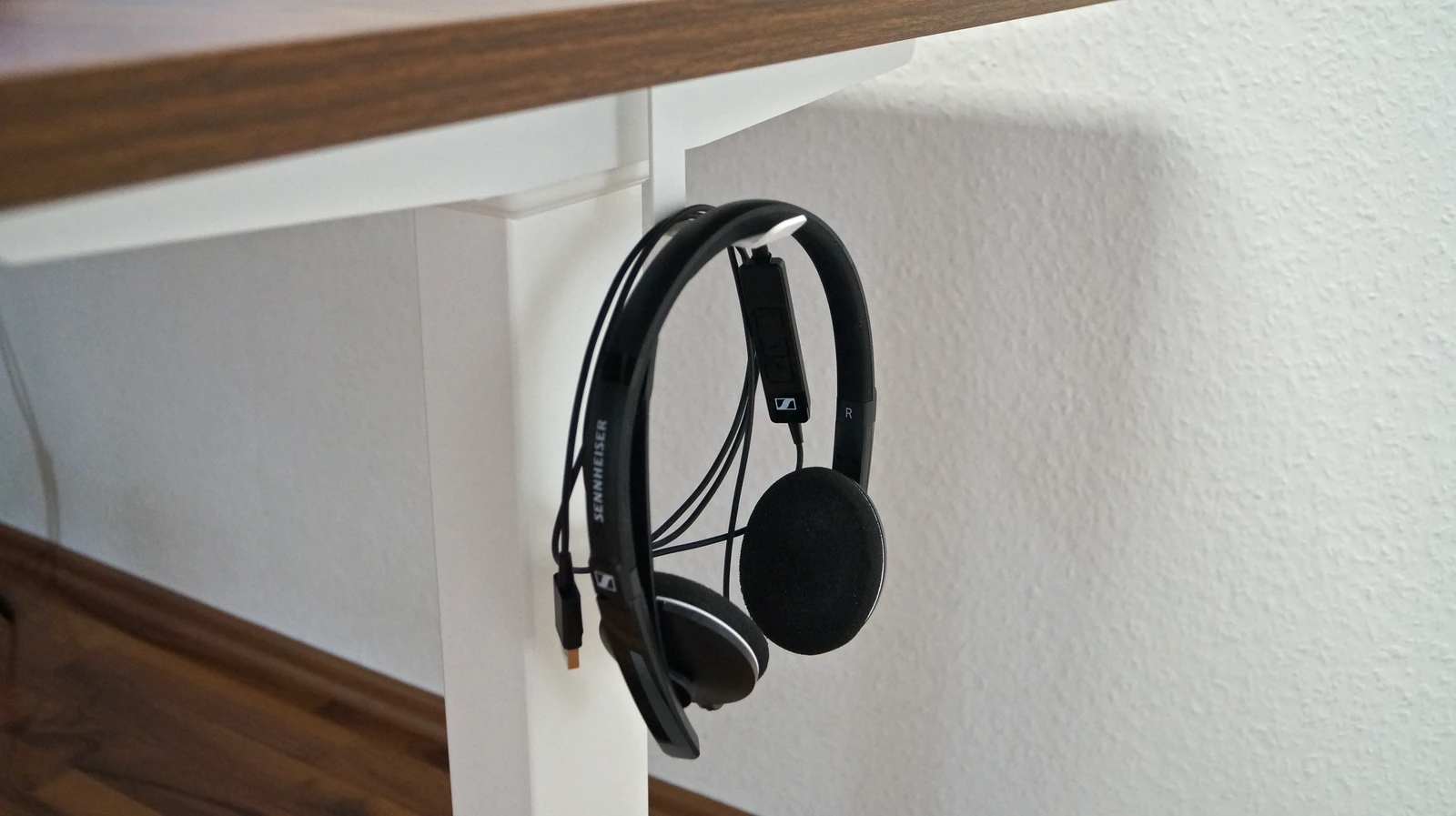 Headset hängt am entsprechenden Haken, Blick seitlich auf das rechte Tischbein des CLOUVOU ProDesk