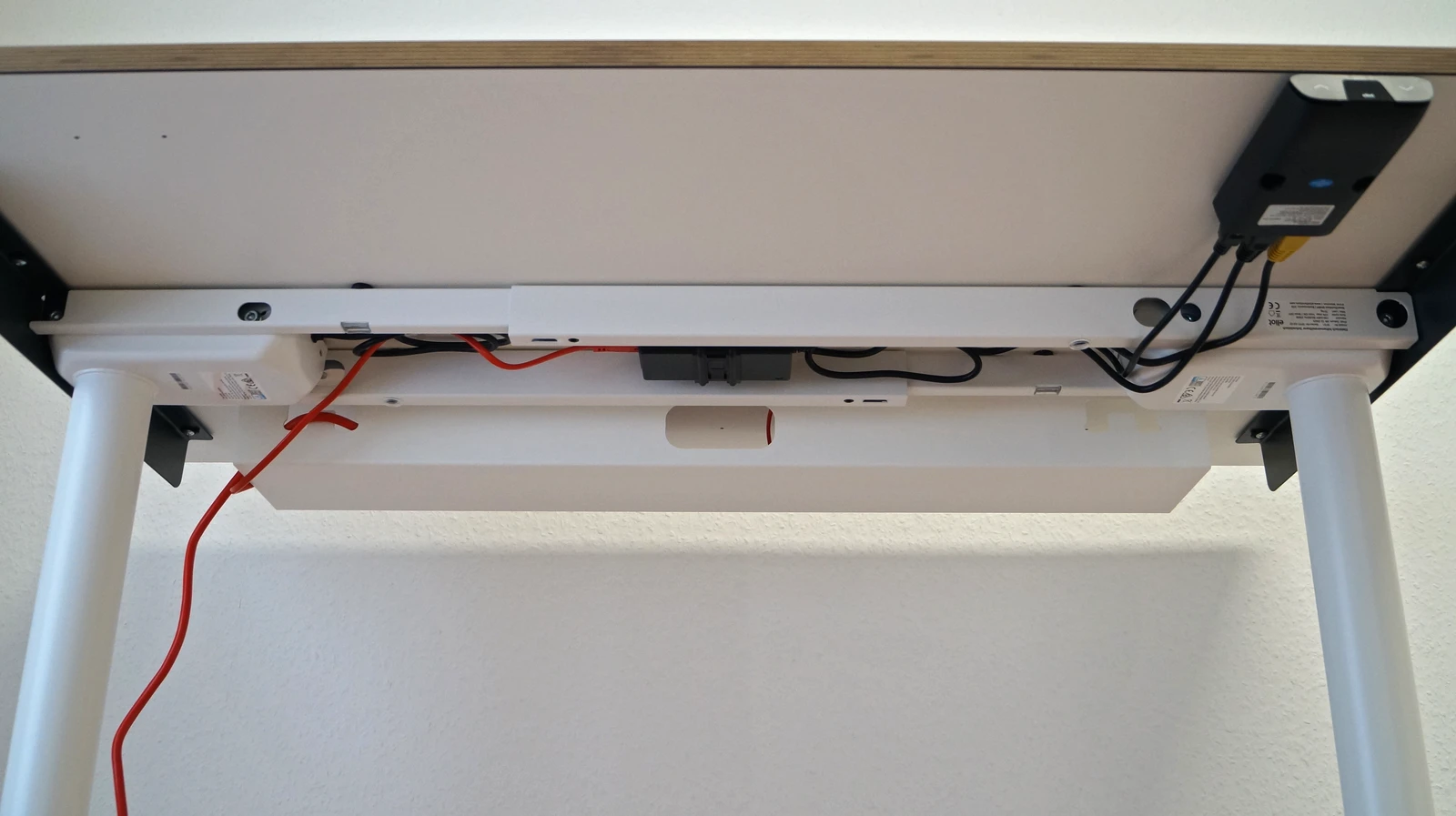 Blick unter den Tisch, Kabelwanne 1cable-light ist erkennbar, links ein rotes Kabel